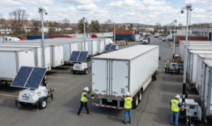 Multiple Renting portable security units are being deployed by workers in a logistics yard, highlighting their flexibility for large-scale security needs.