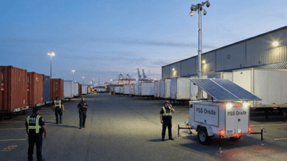 A series of five images showing PSS Onsite solar-powered mobile surveillance trailers deployed in various locations at dusk or dawn. The trailers, equipped with solar panels and tall masts featuring floodlights and cameras, are shown in a Costco parking lot, a large truck stop, and a construction site in an urban area. Security guards wearing high-visibility vests are present in all the images, observing the surroundings.